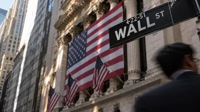 Blurred pedestrian passes the Wall Street sign and a giant American flag on the New York Stock Exchange facade