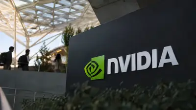 Employees walk past a large Nvidia logo sign at a corporate campus entrance
